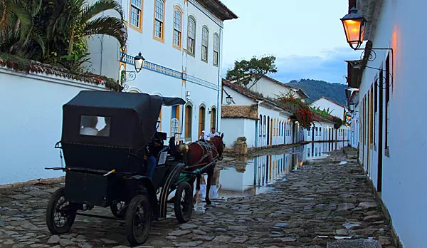 Charrete passando por rua de pedra no centro histórico de Paraty, com casas coloniais brancas